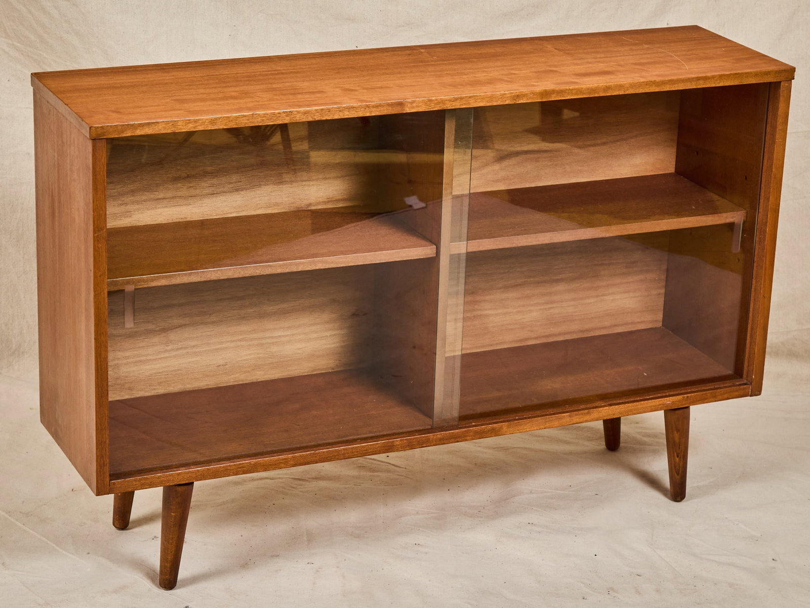 ENGLISH MODERN CABINET with SLIDING GLASS DOORS: Partitioned in (2) sections each with a shelf. With BSI Kitemark quality mark on back. 27 1/2 x 42 x 11 inches.