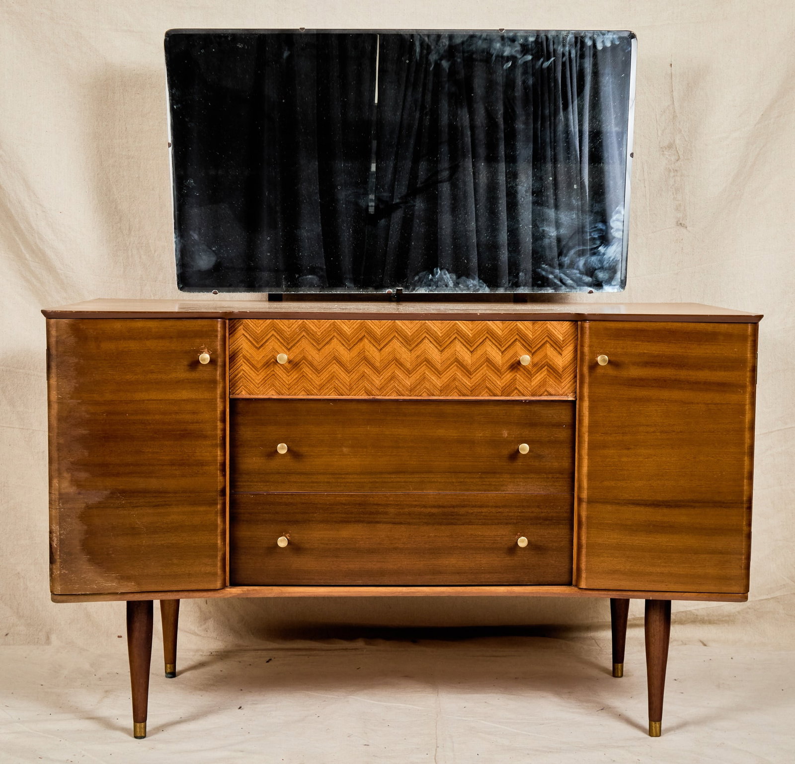 UNIFLEX MID-CENTURY VANITY with MARQUETRY INLAY: Beveled glass mirror, irregular shaped case with (2) cabinets on either side and (3) central drawers including (1) with marquetry inlay. 50 x 46 x 20 1/2 inches.