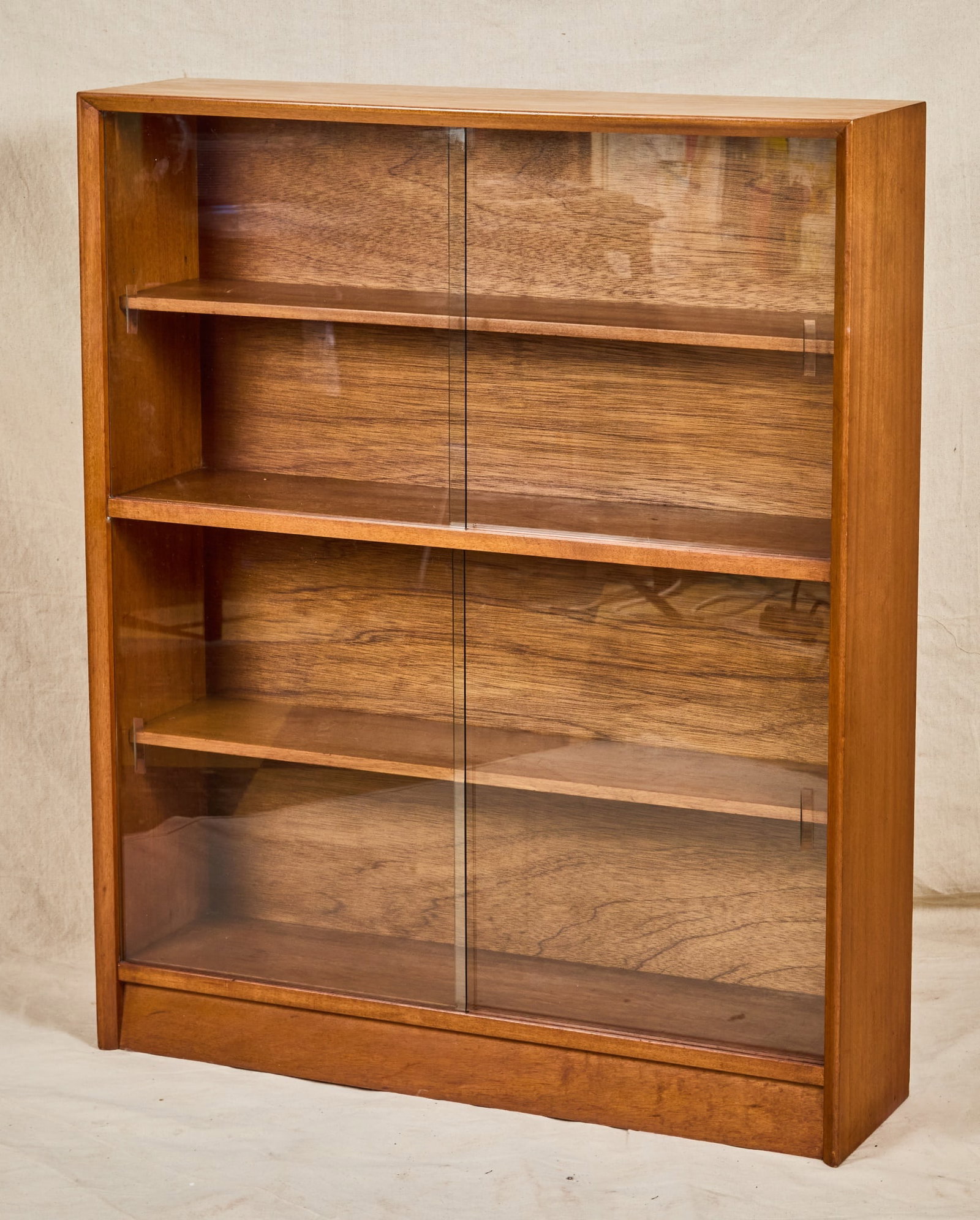 HERBERT GIBBS MID-CENTURY TEAK BOOKCASE: With sliding glass doors, original label on back. 44 x 36 x 9 1/2 inches.
