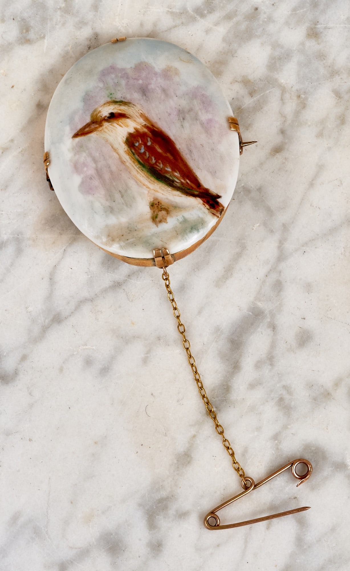 SIGNED 15K & HAND PAINTED PORCELAIN KOOKABURRA PIN: Hand painted porcelain kookaburra plaque signed BB/BK Davis set in 15k gold marked "Christian" with safety pin chain. 1 3/4 x 1 1/2 inches. 9 dwt gross weight.