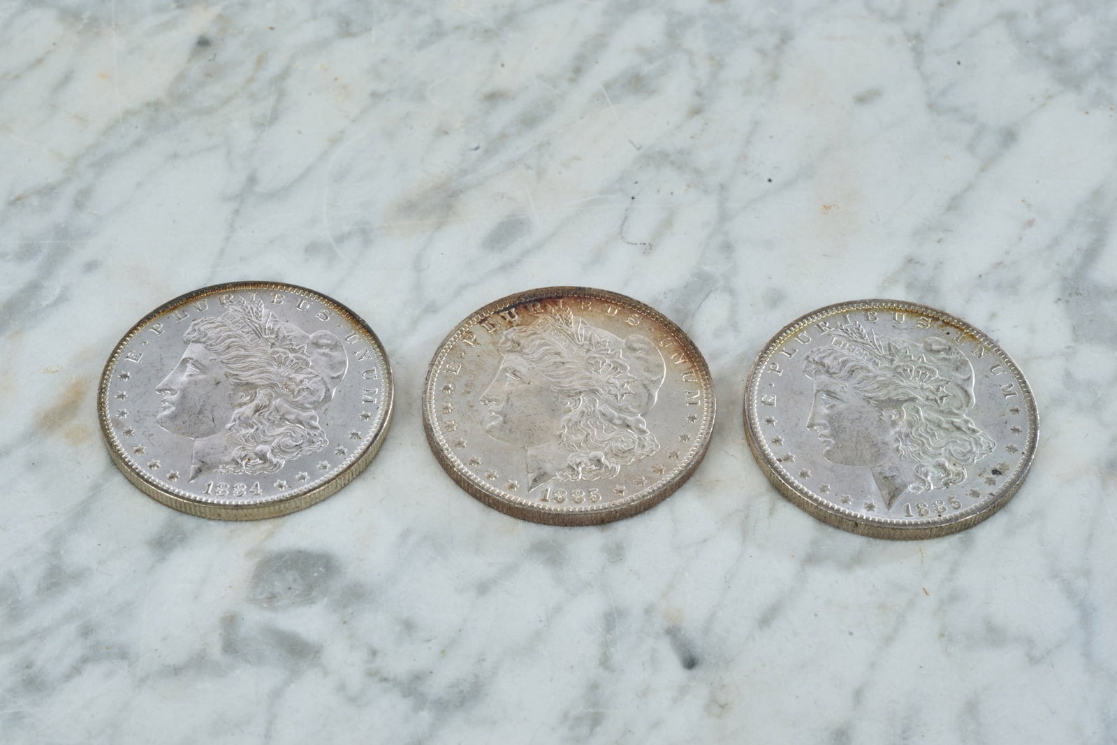 (3) US MORGAN SILVER DOLLARS - (2) 1885 O & 1884 O: 1 1/2 inches.