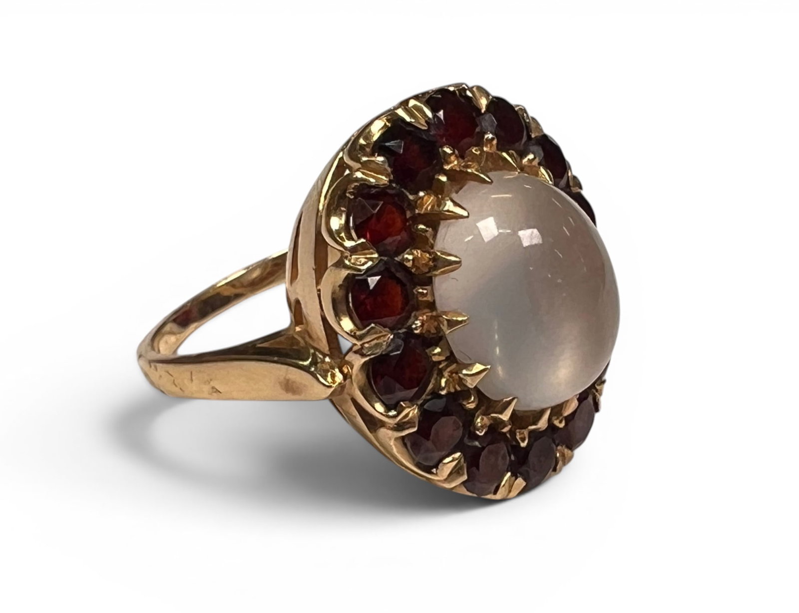 14K GOLD MOON STONE & GARNET COCKTAIL RING: Marked 14k. Central moon stone surrounded by garnets. 5.9 dwt. Size 7 1/2 Condition: Good
