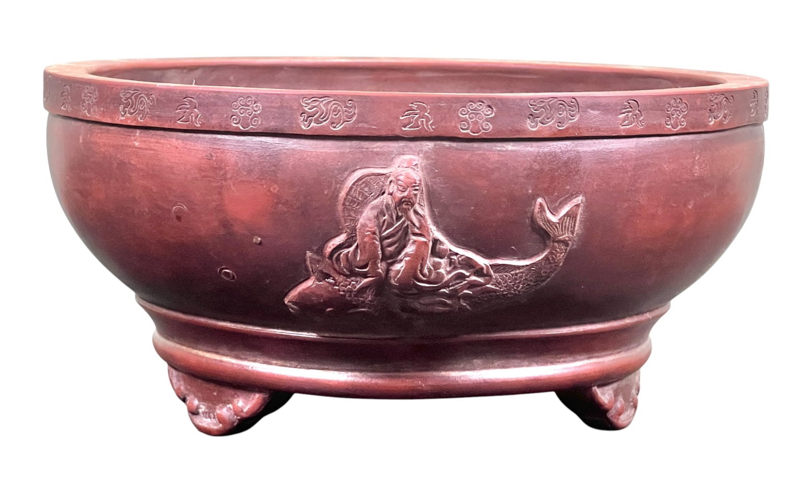 SIGNED CHINESE EARTHENWARE PLANTER with IMMORTAL: A Chinese earthenware planter in red wash with symbols incised to the rim and the immortal Kinko in relief, signed in character under base. 4 x 8 1/4 inches.