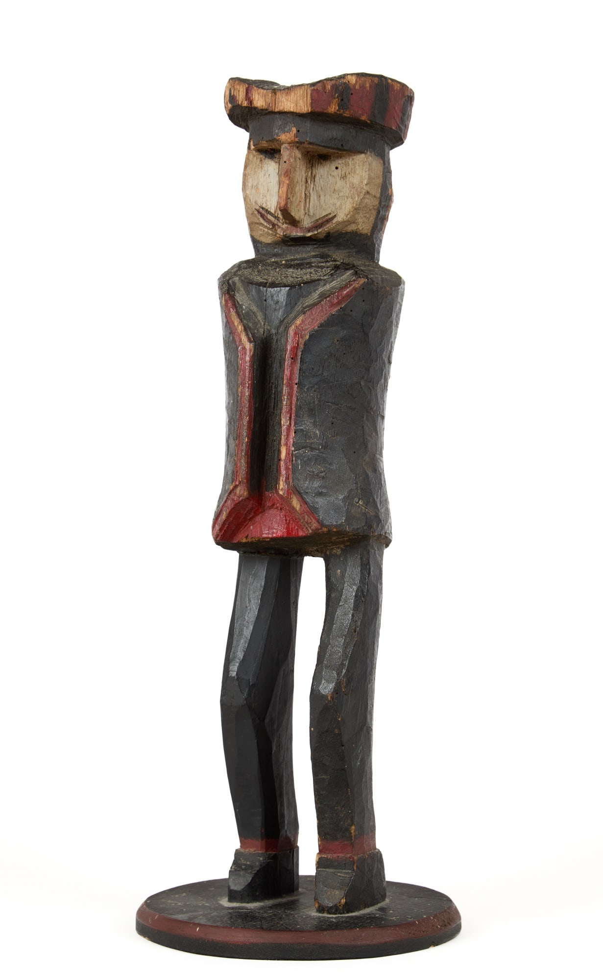(19th/20th c) CARVED & PAINTED FOLK ART FIGURE: Carved & painted folk art figure of a man with sharp nose wearing a black jacket with red trim and a Tam-o-Shanter. Fixed to a wooden base with roseheaded nails. 15 x 6 inches.