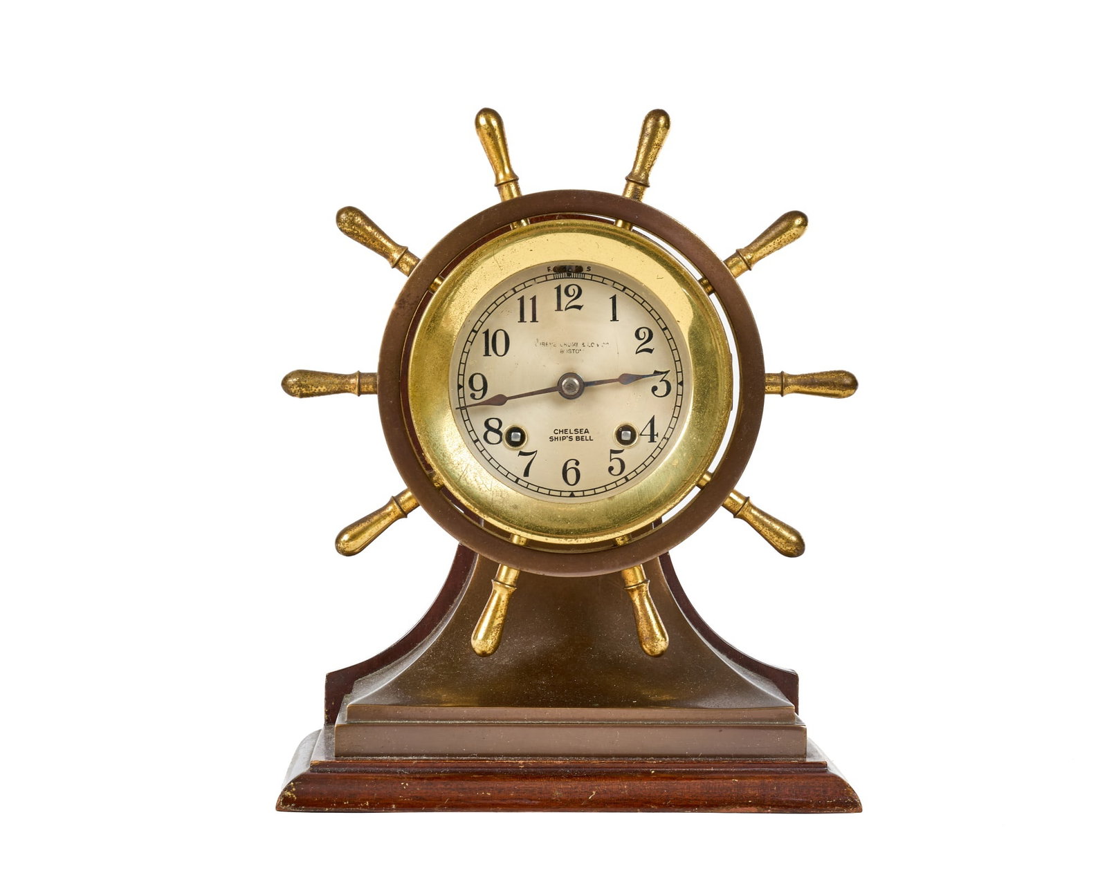 SHREVE CRUMP & LOW CHELSEA SHIPS BELL CLOCK: 4 1/2 inch brass & bronze ships wheel case on wooden base, 3 inch engraved silver dial with Shreve, Crump, & Low Co. retailers mark. Serial no. 238251. 10 x 8 x 4 1/4 inches.