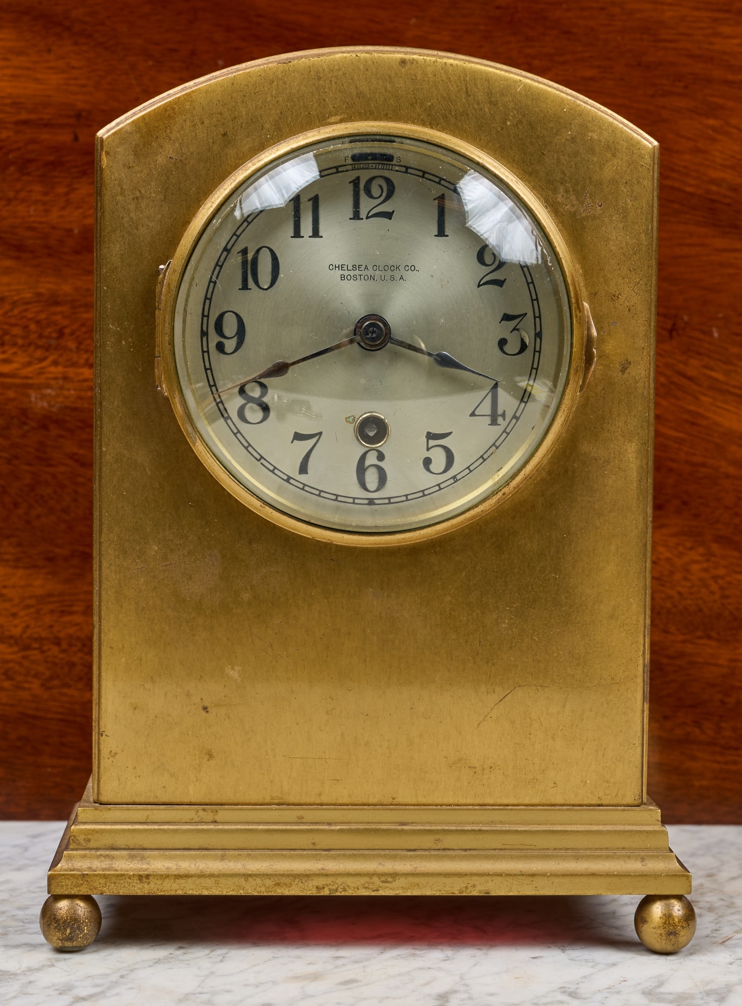 CHELSEA CLOCK CO. BRASS "SHERATON" MANTEL CLOCK: Brass case, 3 1/2 inch engraved silver dial, works serial no. 104026. 9 1/2 x 7 x 4 inches.