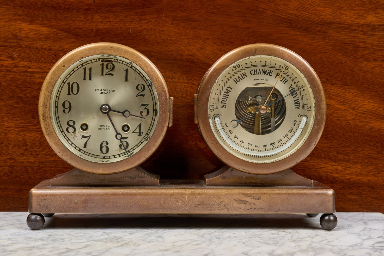 SPAULDING & CO. CHELSEA SHIPS BELL CLOCK BAROMETER: 5 inch bronze cases with beveled glass, 3 3/4 inch engraved silver dial with Spaulding & Co. (Chicago) retailers mark. Serial no. 151121, circa 1920-24. 6 1/2 x 11 3/4 x 3 3/4 inches.