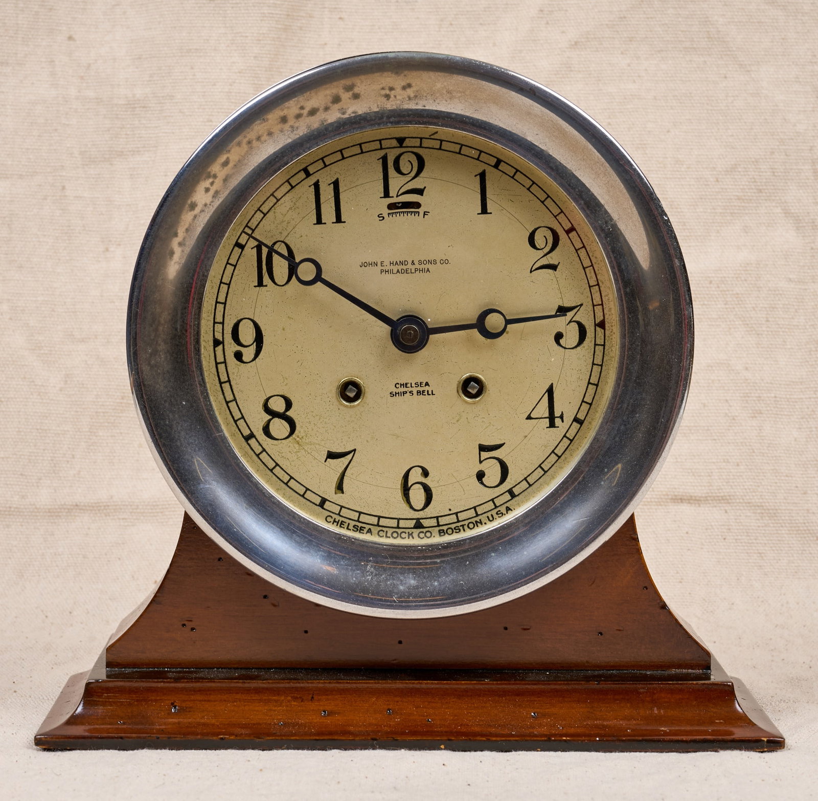 JOHN E. HAND & SONS CHELSEA SHIPS BELL CLOCK: 7 1/4 inch nickel plated case, 5 inch engraved silver dial with John E. Hand & Sons Co. retailers mark and Breguet hands. Serial no. 148970. 7 1/4 x 3 1/4 inches.