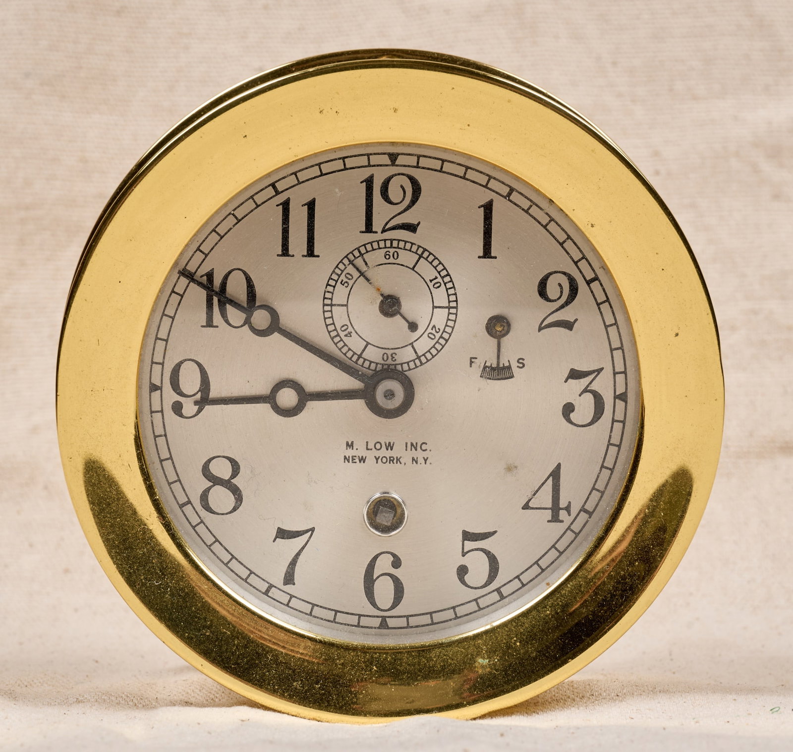 M. LOW INC. CHELSEA CLOCK: 5 1/4 inch brass case, 3 3/4 inch engraved silver dial with M. Low Inc. (New York) retailers mark and Breguet hands. Serial no. 35860, circa 1905-09. 5 1/4 x 2 1/4 inches.