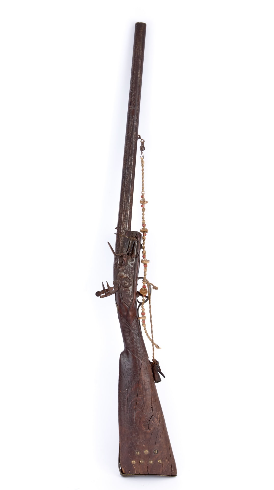 T. KETLAND PLAINS INDIANS FLINTLOCK RIFLE: With braided fibre, bead, and shell casing tassel. 34 1/2 inches; 18 1/2 inch barrel.
