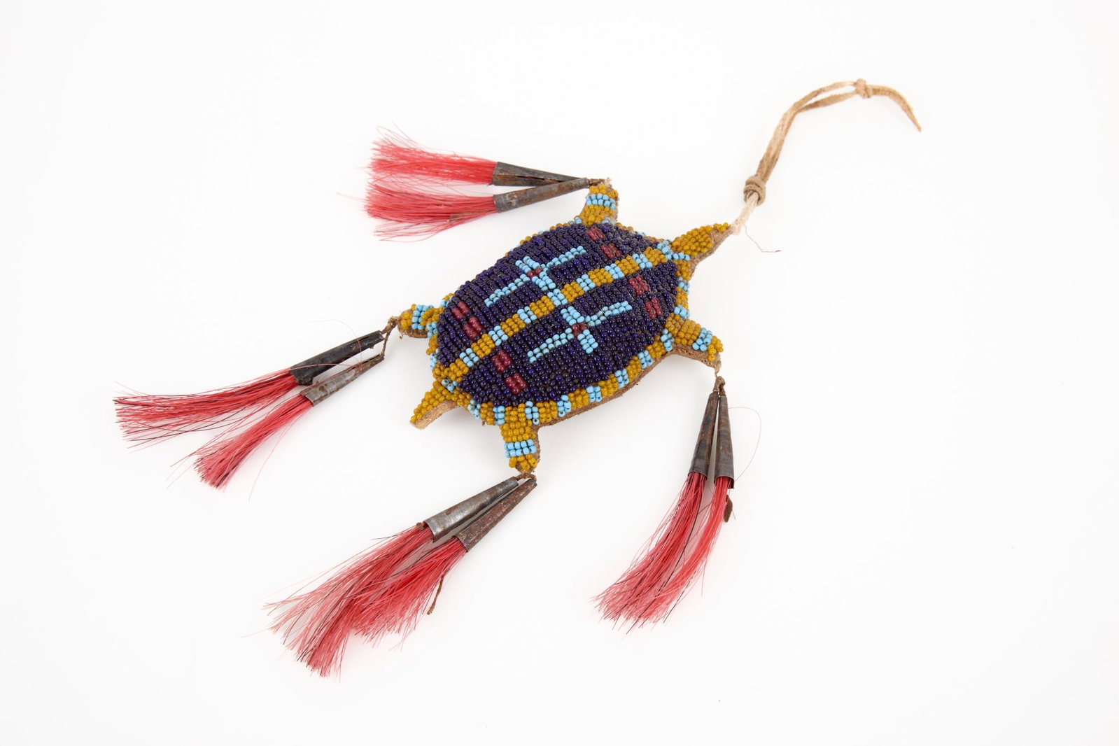 PLAINS INDIANS BEADWORK UMBILICAL TURTLE FETISH: Tanned hide turtle form umbilical fetish with geometric polychrome beadwork & tin cone tassels with dyed horse hair. 4 1/2 x 3 inches.
