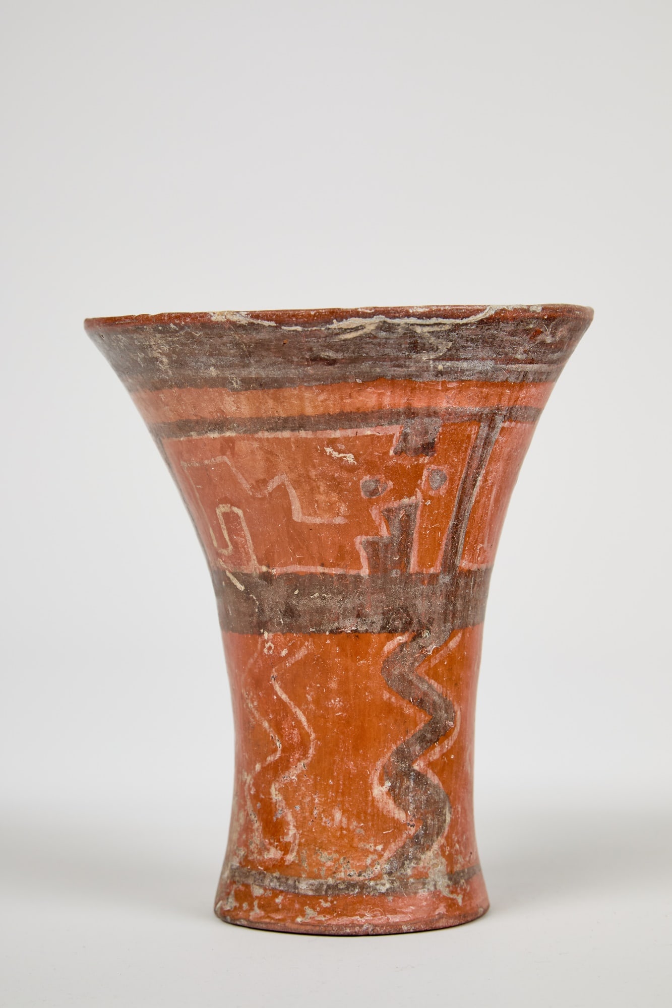 TIWANAKU PRE-COLUMBIAN PAINTED EARTHENWARE QERO: Tiwanaku Pre-Columbian painted earthenware qero cup with flared rim and painted with geometric designs. 6 3/4 x 5 3/4 inches.