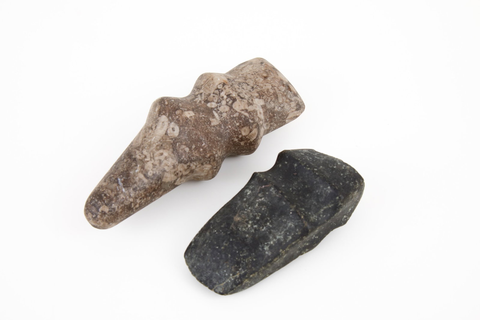 (2) NATIVE AMERICAN STONE TOOL ARTIFACTS/CELTS: (1) ax head form carved from deep green steatite & (1) pickax form carved from marine shell fossil stone. 5 1/2 inches.