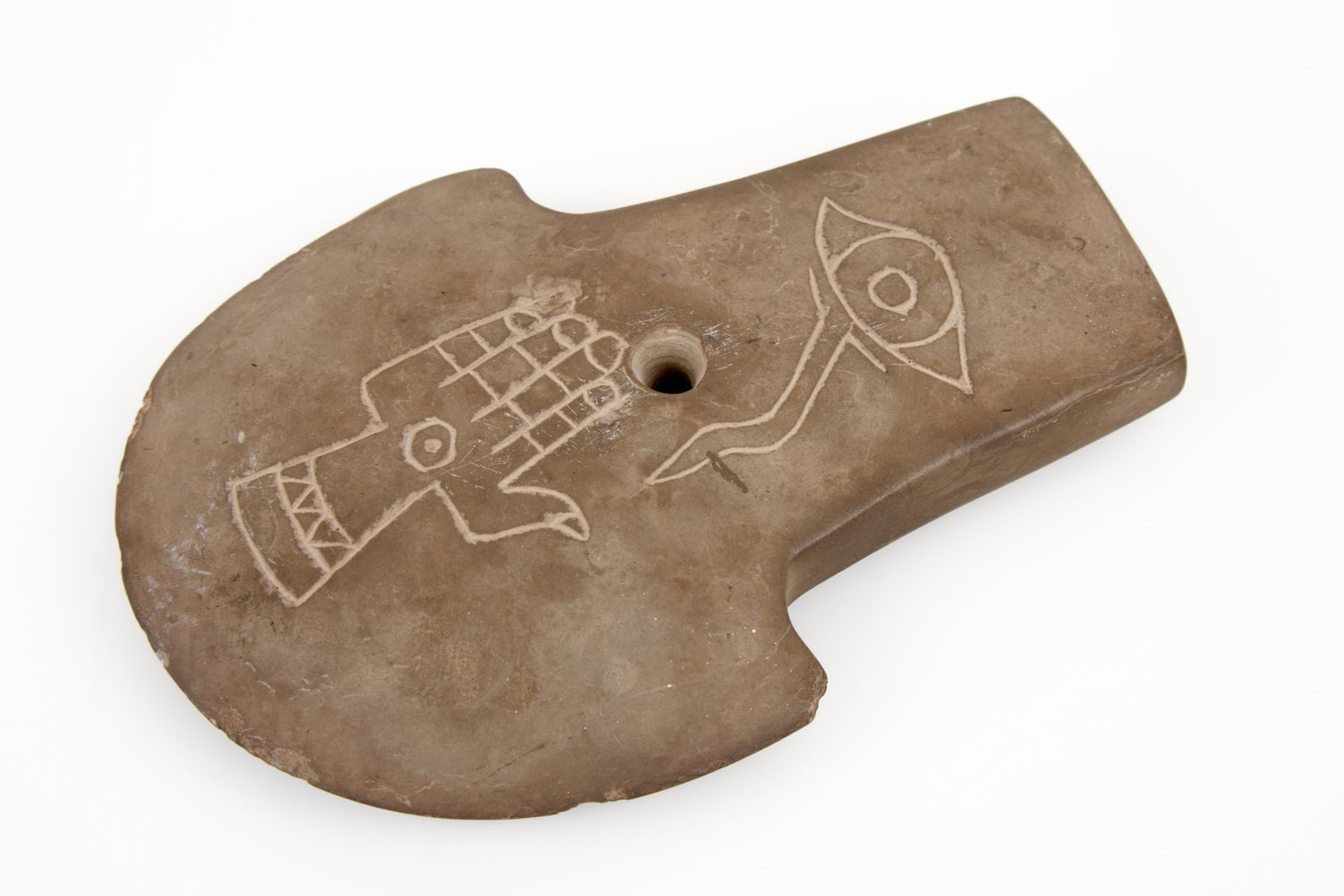 BARTOW CO. (GA) DRILLED STONE AXE: Native American drilled stone axe with carved watchful eye, hand, and portrait of Native American. Uncovered in Bartow Co. (GA). 7 1/4 x 5 1/4 inches.