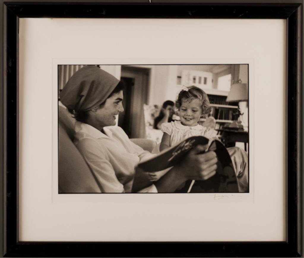 (26) "A Tribute to Jackie" Jacques Lowe: "Jackie and Caroline reading together in foreground while Jack is working in the background" Hyannis Port, MA 1960. 11 1/2 x 17 inch photograph signed Jacques Lowe. 22 1/2 x 26 1/2 inches framed. (min