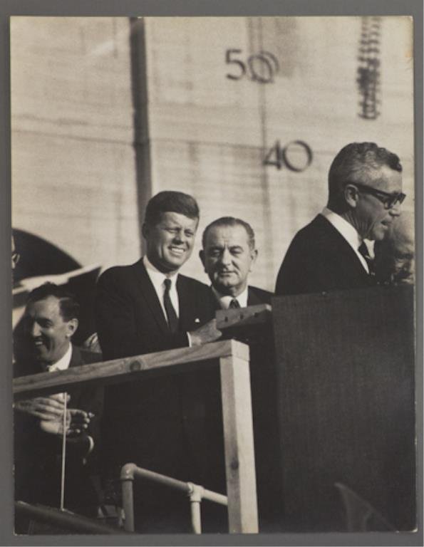 Photograph of Kennedy and Johnson at DNC: (1) Large format photograph of John F. Kennedy & Lyndon B. Johnson behind podium with Ed Muskie in background at the Democratic National Convention, 13 3/4 x 10 3/4 inches, stamped "photo by Bill Brid