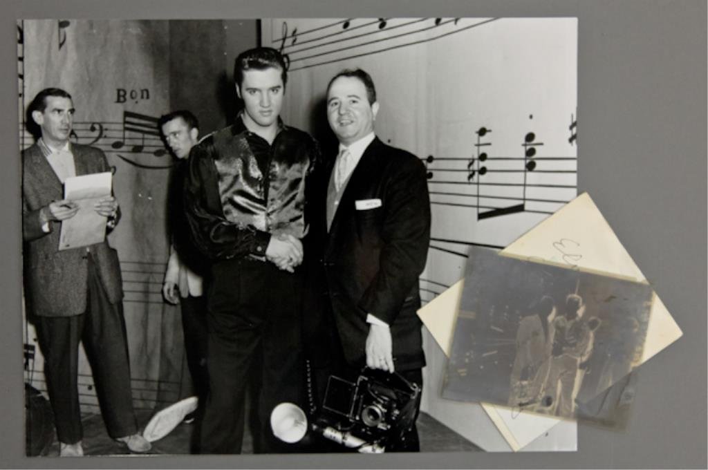 Elvis Presley & Frank Mastro: (1) 4 x 5 inch negative of Elvis Presley and Frank Mastro, together with (1) 11 x 14 photograph reprint. Elvis is shaking hands with photographer Frank Mastro; two of Elvis's backup singers are in the