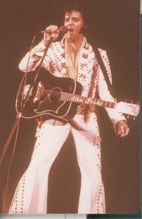 Elvis Presley: (1) 35mm color transparency of Elvis Presley, together with a 4 x 6 inch photograph reprint. Frame of transparency labeled "Pictorial Parade" and "fotos international". Elvis on stage with microphone 