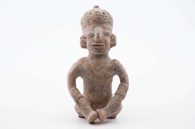 Primitive Clay Figure of Seated Man: Hollow clay figure of seated man with hands on his knees. Whistles. 8" high. Condition: Torso has a crack.
