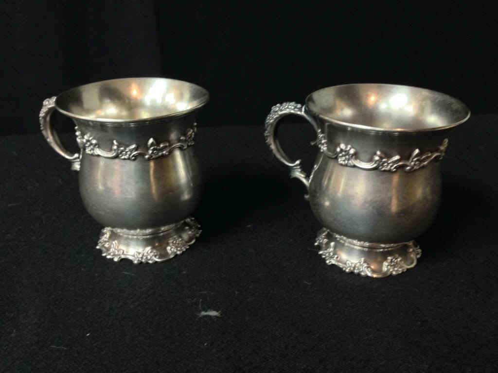 Pair Tiffany Sterling Cups: Pair of sterling silver cups with floral and scroll border on scalloped foot ring, top and handle marked Tiffany & Co. Makers. 4 1/2 inches (inclusive of handles) x 3 1/2 inches. Condition: Good