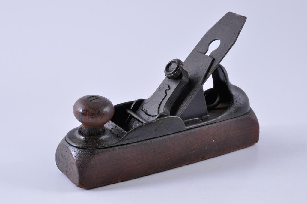 Stanley Wood Bottom #122 Plane with a Liberty Bel: 8” x 2” Stanley #122 Plane, made circa 1876. The front knob has a chip at the base, and there is a crack in the sole. Condition: fair