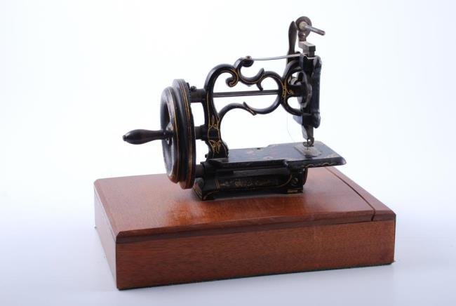 Raymond Hand Operated Sewing Machine 1861: Patented 1861 Small Iron Paint Decorated Hand Operated Sewing Machine by Charles Raymond of Brattleboro, VT. Height 7 1/2 inches not including base. Condition: Good: Minor paint loss. Missing brass th