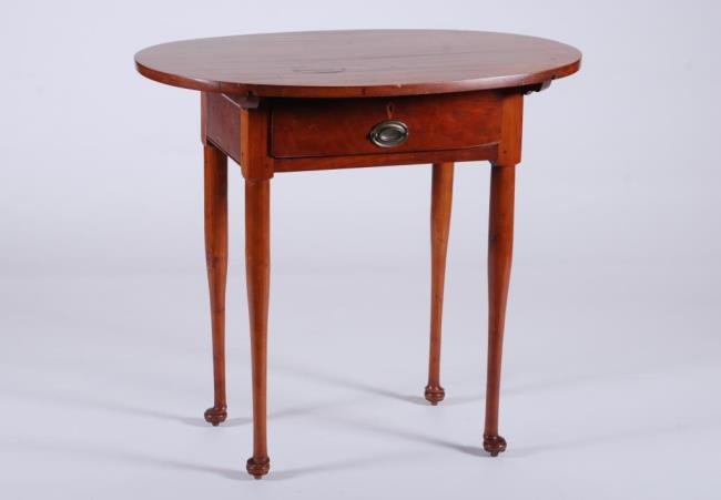Cherry Queen Anne One-Drawer Tea Table: Oval top over a rectangular base with one-drawer, straight turned legs and pad feet. 31 x 33 x 24 inches. Condition: Restored, stain and minor scratches to top