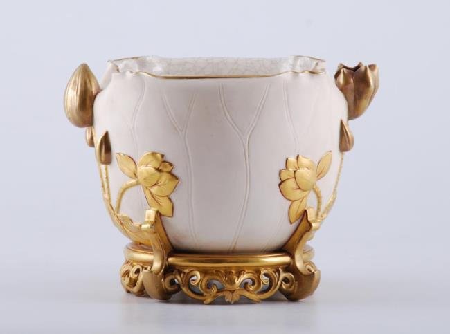 Royal Worcester Water Lily Planter: Cream glazed planter with bas relief and applied water lily motif resting on an integral Asian inspired gold stand. Craquelure interior. Signed. Height 8 inches. Width 11 1/2 inches. Condition: Good, 