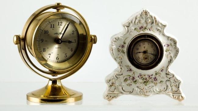 GIMBALED SETH THOMAS CLOCK & A CERAMIC SHELF CLOCK: Quartz Seth Thomas desk clock with 3 1/2 inch dial. Together with a ceramic shelf clock with a Waterbury Clock Co. movement. Height 8 and 7 1/4 inches.