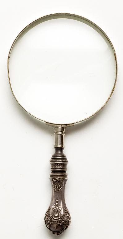 MAGNIFYING GLASS WITH STERLING REPOUSSE HANDLE: Weighted sterling silver handle marked "patd. sterling". Length 8 1/2 inches