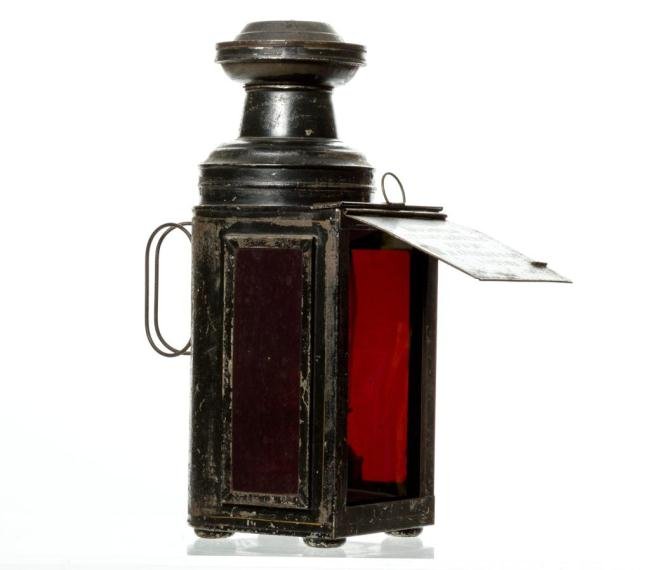 "VENUS LANTERN" BY H. CODMAN & CO. BOSTON: Black painted tin lantern support (3) panes of red glass. Front pane slides up and off to allow access to the signed "Venus" kerosene burner with blown molded chimney. A hinged front visor is stencile