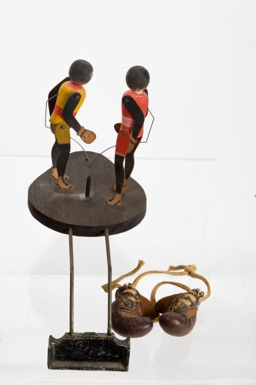 BLACK AMERICANA NATIONAL TOY CO. MECHANICAL BOXERS: Animated boxer novelty toy is designed to be placed on a record player which drives boxer's mechanism. A small pair or boxing gloves drape from offset weight. 7 x 9 inches