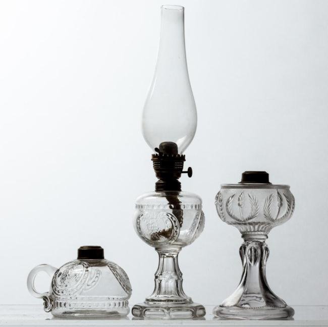CENTRAL GLASS CO. STEM & FINGER LAMPS WITH A THIRD: (2) Stem and finger lamps with fonts embossed three times with wheat in shield and band of beads motif. Together with a stem lamp with font embossed with a ring of torches and laurels on a stippled gr