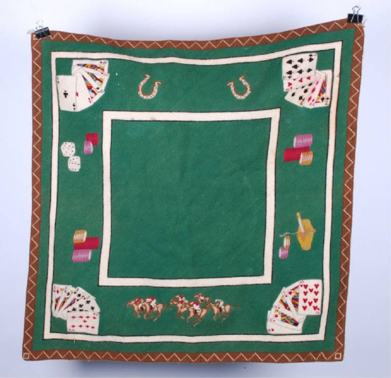 (Early 20th c.) Embroidered Poker Table Theme Mat: Well executed wool and petit point embroidery depicting poker table top with cards, chips, dice, race horses and horse shoes. 30 x 30 inches Condition: Good, slight fray to (1) corner