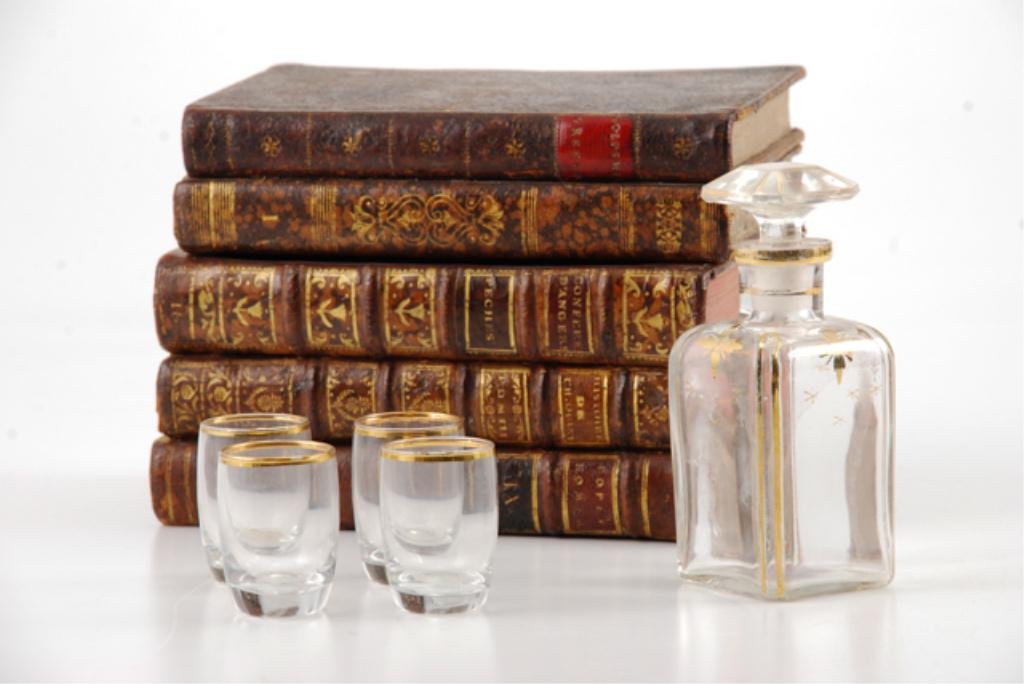 Antique Cordial Set in Book Form Case: Pages of antique books were hollowed to fit a decanter and (4) glasses trimmed with gold. Case dimensions are 5 x 6 x 4 inches. Condition: Chip to rim of creamer, sugar bowl minor manufacturing rim ch