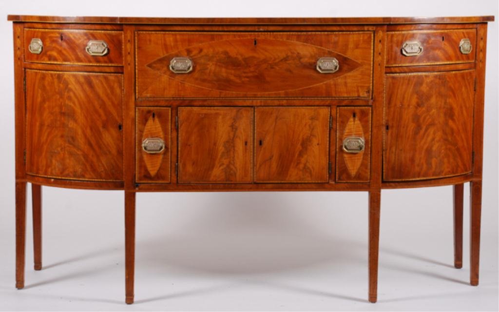 (19th c.) Hepplewhite Mahogany Sideboard: "D" form sideboard with string inlay, bell flower, crotch mahogany and satinwood elliptical veneers. Top drawer falls front to drawers for flatware, (2) lower drawers open to receive liquors and wines