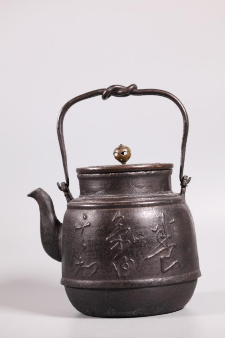 Fine Japanese Cast Iron Tetsubin or Teapot: Fine Japanese Cast Iron Tetsubin or Teapot, the front with a cast pomegranate in relief and the reverse with calligraphy in "Grass Script." The handle in wrought iron forming a square-knot at the cent