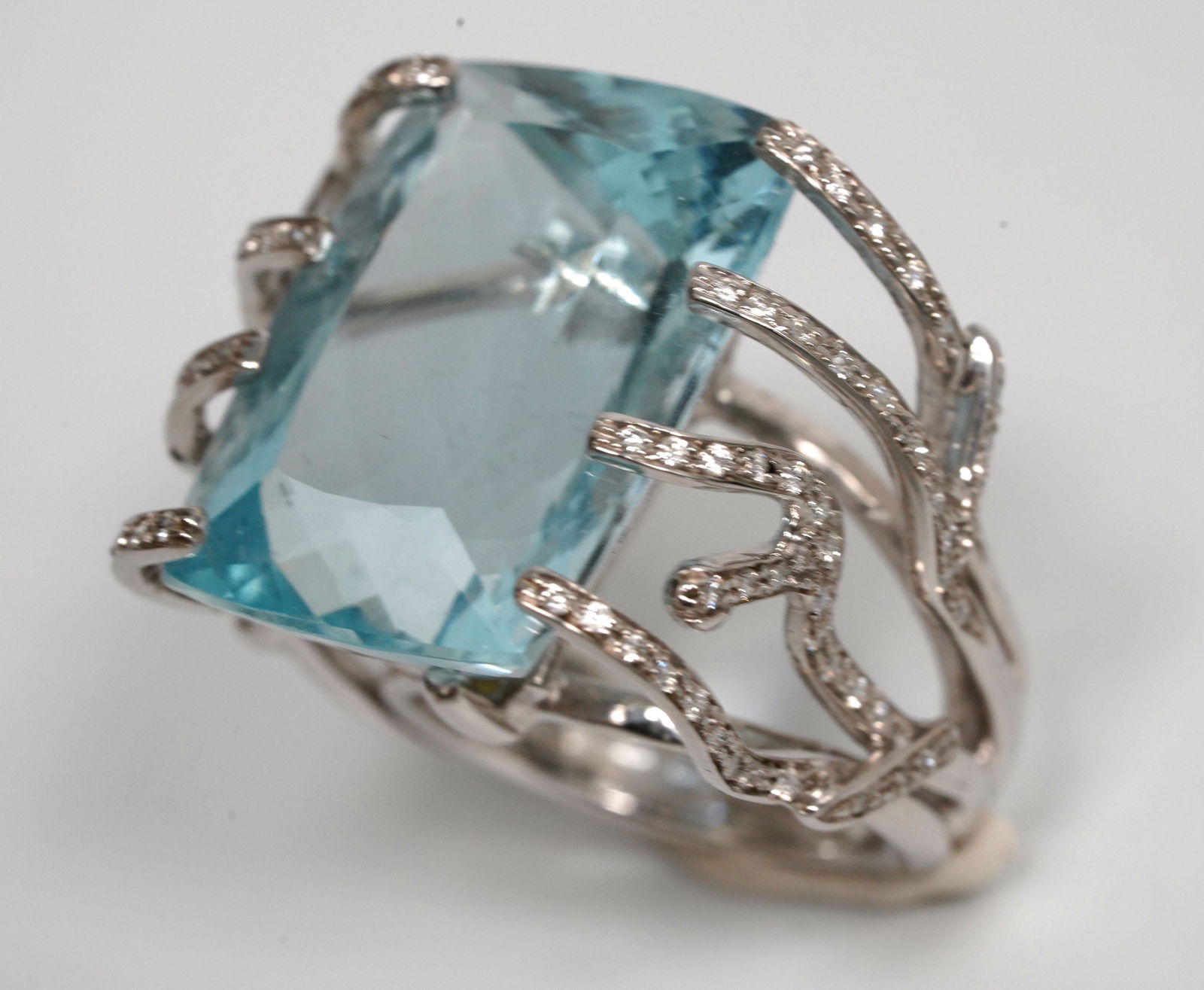 Cushion Cut Aquamarine 18K White Gold Ring: Cushion Cut Aquamarine in a setting of 18K White Gold Ring with "coral" shaped branches in small diamonds. Total weight 29.5 grams. US ring size 8 1/2. Good condition with light age related wear. ____