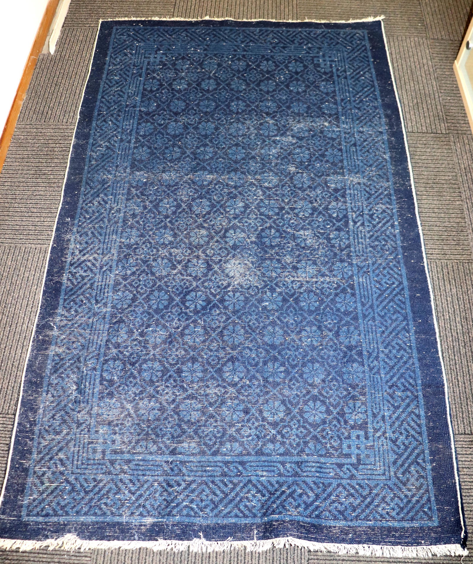 Chinese Indigo Wool Carpet with Key Fret Borders: Chinese Indigo Colored Wool Carpet with Key Fret Borders in dark blue on light blue. Age related wear; both ends with shortened fringe and one triangular spot of pile missing from one short section of