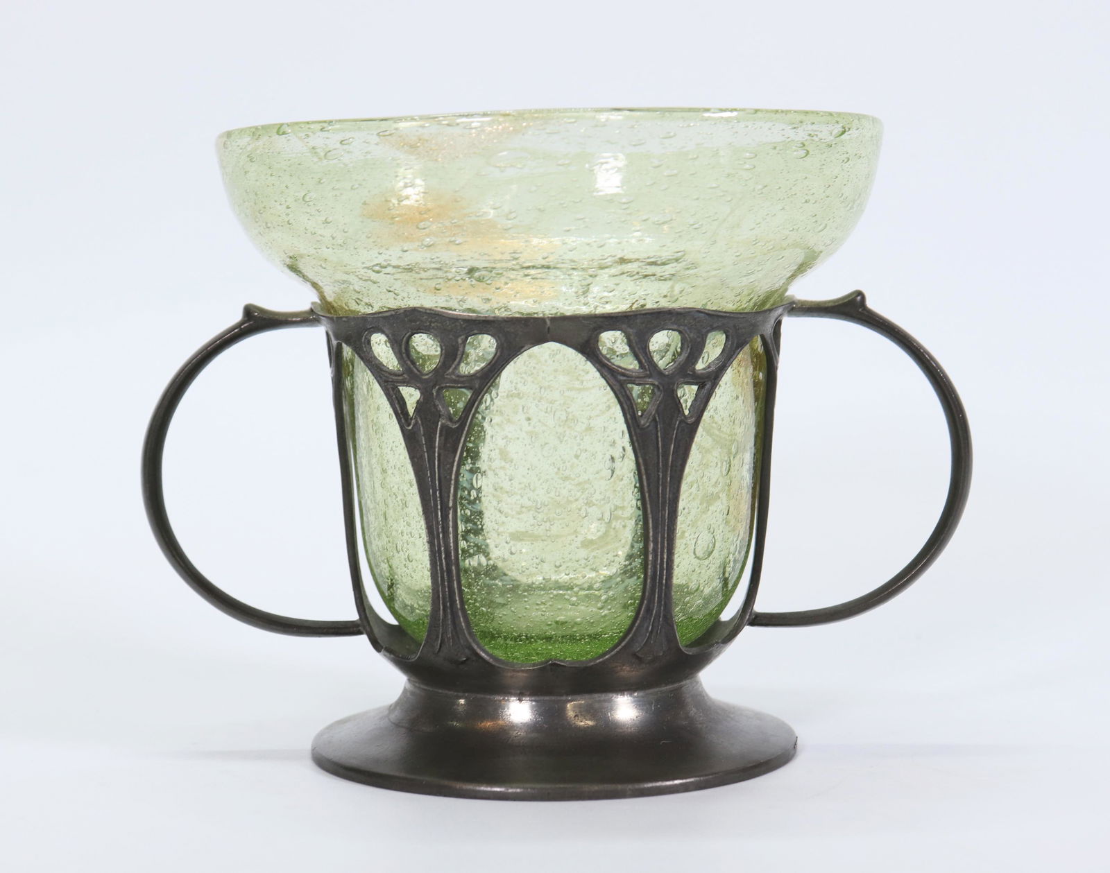 A. Knox Liberty & Co "TUDRIC" Glass & Pewter Coupe: Art Nouveau / Celtic Revival Pewter ware for Liberty & Co. of London by Archibald Knox in a pale green bubble and gold splashed blown glass liner fitted into a 6 arched Pewter 2 handled Coupe with fla