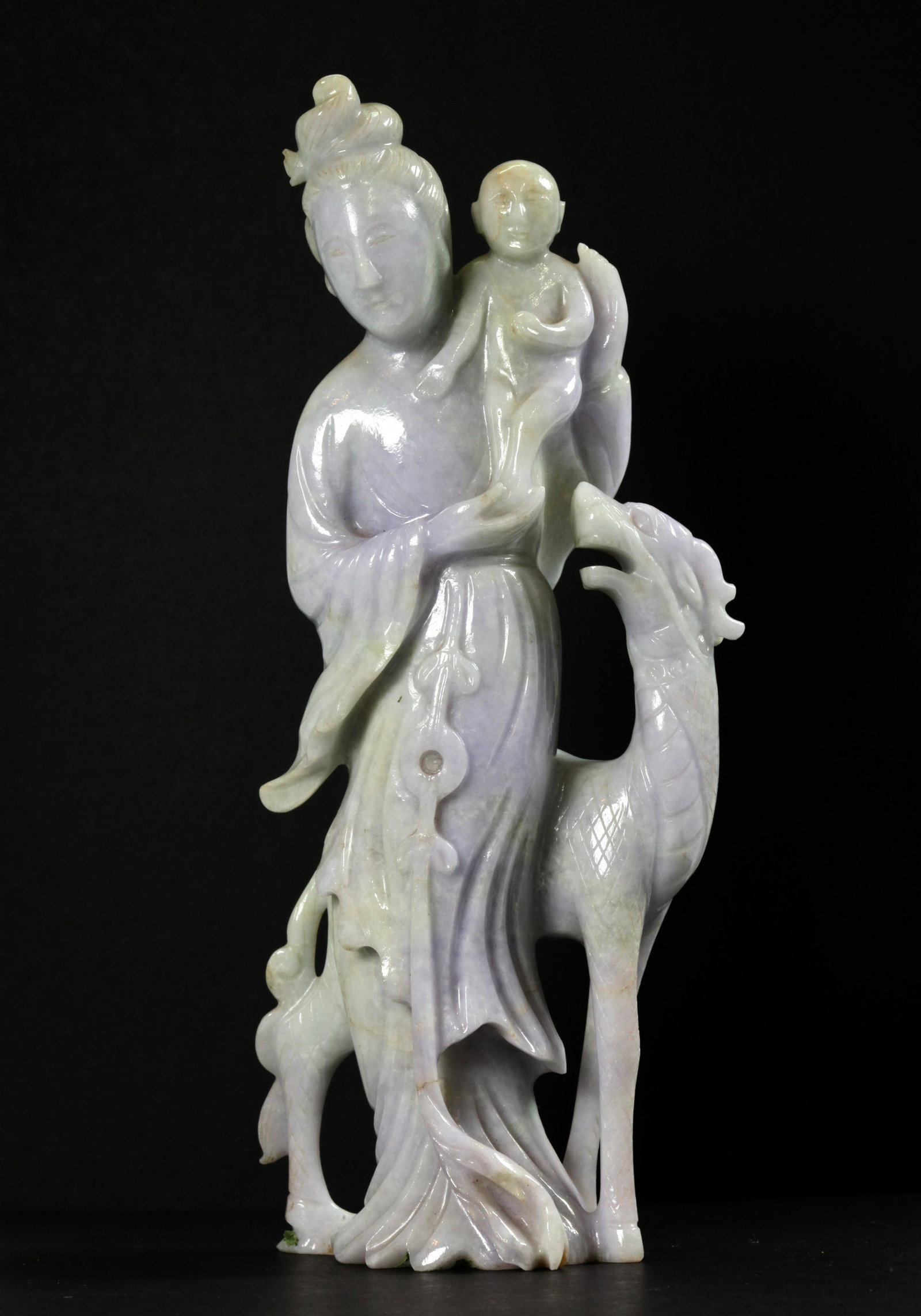Chinese Carved Jadeite Lady Immortal Boy & Beast: Chinese Pale green and Pale lavender Jadeite carved Lady Immortal, a young Boy in her arms & a hoofed and horned Beast at her feet. Height 8 1/4 inches (21 cm.).