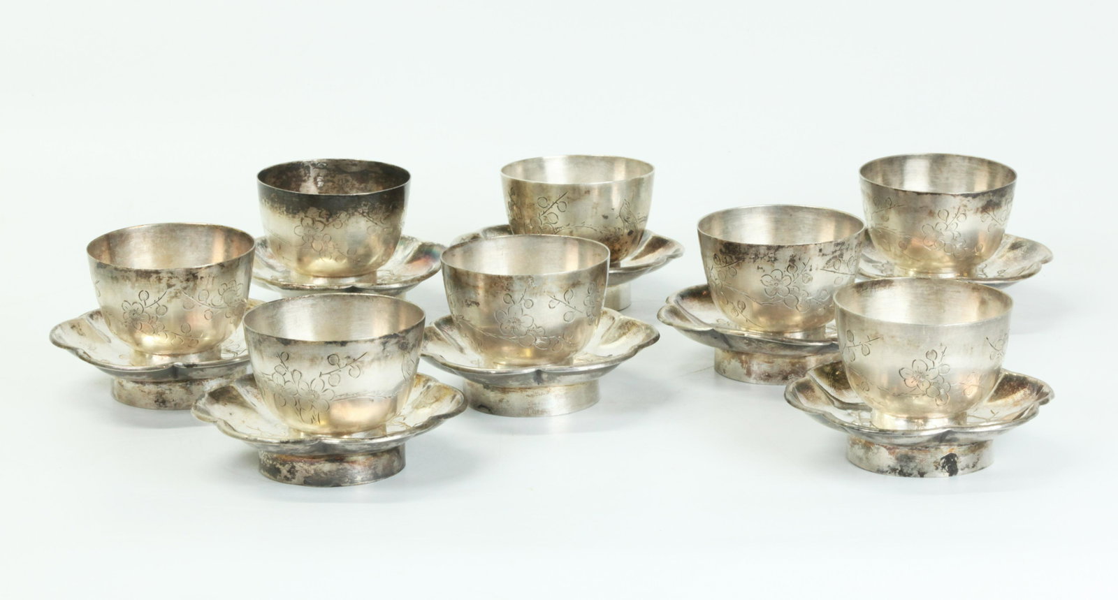 8 Chinese Silver Plumb Blossom Wine Cups 8 Saucers: 8 Chinese Silver Wine Cups incised with Birds and Blossoming Branches with silver hallmarks to foot rings; together with 8 six Petal Saucers incised with Birds & Blossoms and with silver hallmarks to