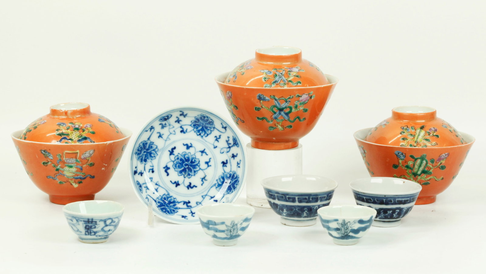 9 Chinese Porcelains 3 Teacups 5 Wine Cups 1 Plate: 9 Chinese Porcelains 3 Teacups and covers with enameled Auspicious Objects on a "Coral" ground, 5 small blue & white Wine Cups, and 1 blue & white Lotus pattern Plate with 4 character Qianlong mark to