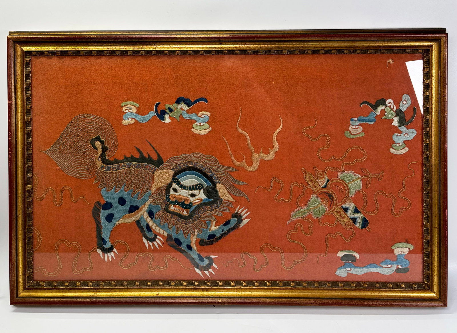 Chinese 19th C Fu Dog and Bat Embroidery: Chinese 19th Century Fu Dog and Bat silk floss and laid gold wrapped thread Embroidery on apricot wool, probably a border fragment; framed to the edges. Height of frame 18 3/4 inches (47.5 cm.) X widt