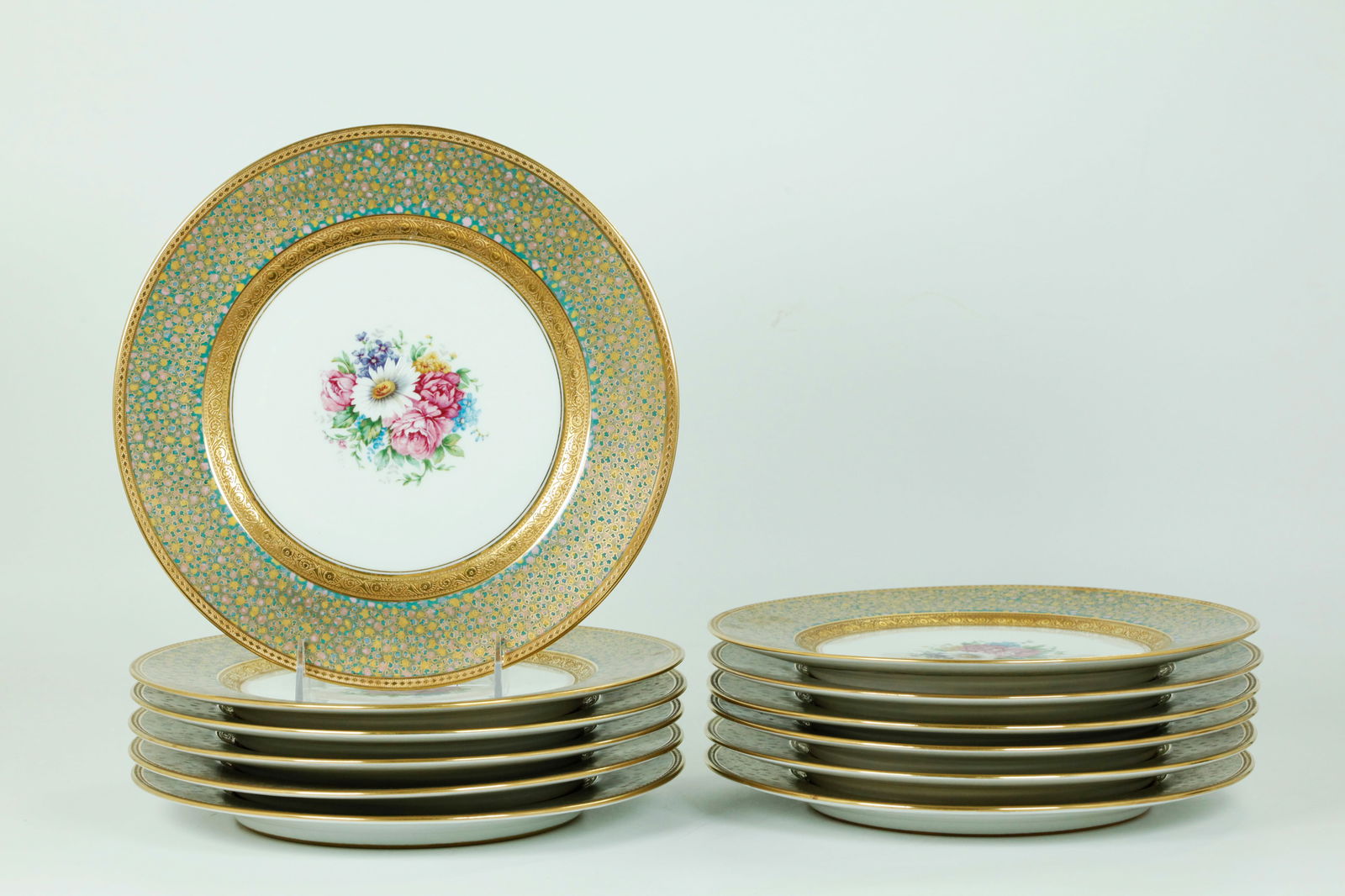 12 Bernardaud 1920's Porcelain Service Plates: 12 Bernardaud, Limoges Enameled & Gilt Porcelain Service Plates circa 1920's, with elaborate borders of etched gold to the edges of small colored enamels in gilt frame patterns, the centers with bouqu