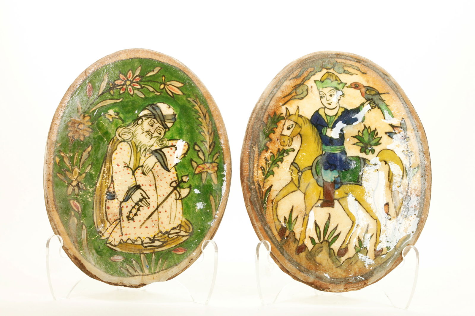 2 Persian Antique Pottery Figural Oval Tiles: 2 Persian Antique Pottery Figural Oval Tiles: a Prince on Horseback with Hunting Falcon on a cream ground and a seated Philosopher in a Garden on a green ground. Height 10 1/4 inches (26 cm.).