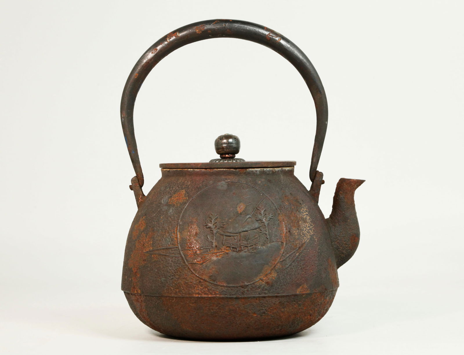 Japanese Cast Iron Tetsubin Teapot; Bronze Cover: Japanese Cast Iron Tetsubin Teapot with a cast scene to one side of a Mountain Viewing Hut, with wrought iron handle with silver inlay and a Bronze Cover with silver finial. Height with handle 9 inche