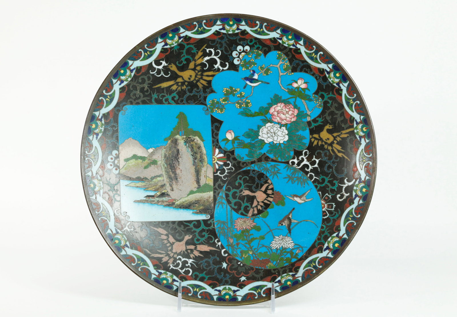 Japanese Meiji Cloisonne & Bronze Display Plate: Japanese Meiji Period (1868-1912) Cloisonne & bronze round display plate with three windows with a Mountain Landscape with bright blue sky, a blossom shape with birds on flowering branches on a bright