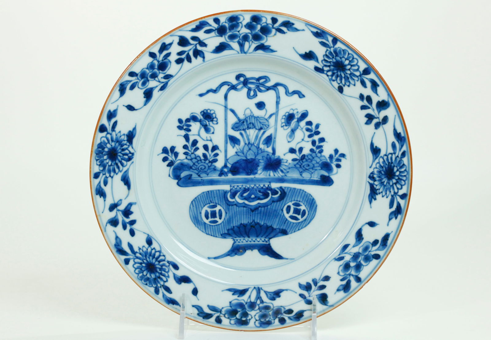 Chinese Kangxi Blue & White Porcelain Basket Plate: Chinese Kangxi circa 1700, Blue & White Porcelain Plate with Flower Basket to center and scrolling flowers with leaves to the edge; the base in clear glaze with a brown slip to the outside edge. Diame