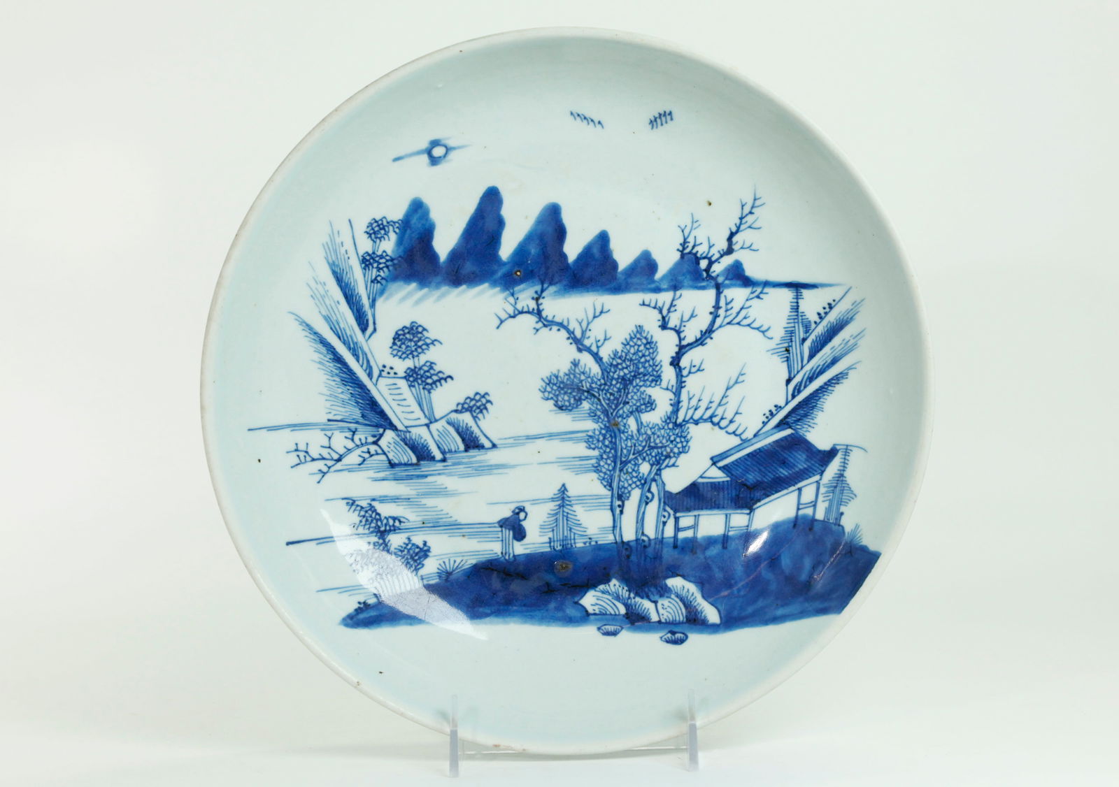 Chinese 18 C Blue White Porcelain Landscape Plate: Chinese 18th Century Blue & White Porcelain Charger or Low Bowl with a Figure at a Pavilion viewing a Mountain Lake, the underside edge with bamboo and the flat recessed base unglazed. Height 2 3/8 in